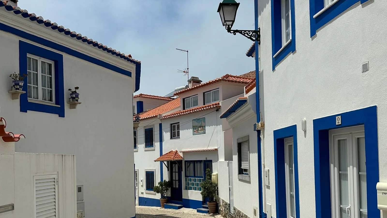 Witgekalkte huizen met blauwe kozijnen in een straat van Ericeira