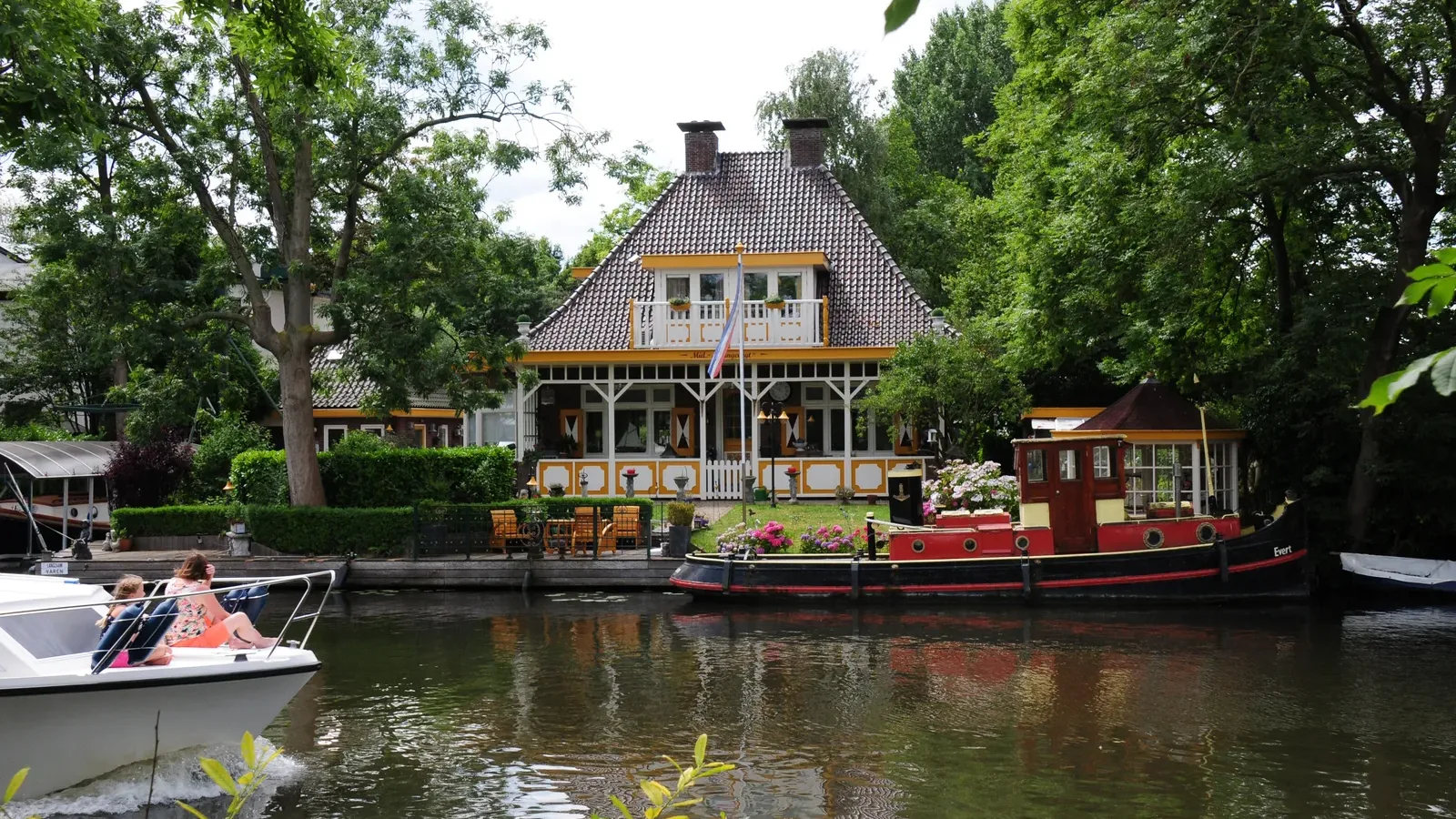 Buitenplaats aan de Vecht met een boot op het water tussen de bomen