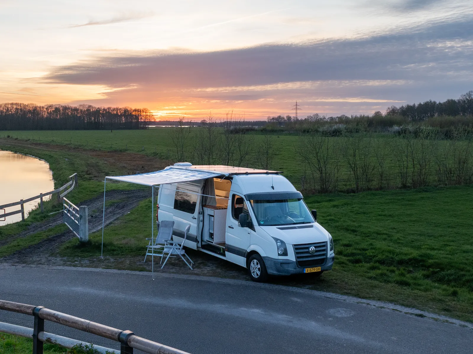 Camperbus geparkeerd op een rustige Nederlandse weg met weilanden op de achtergrond